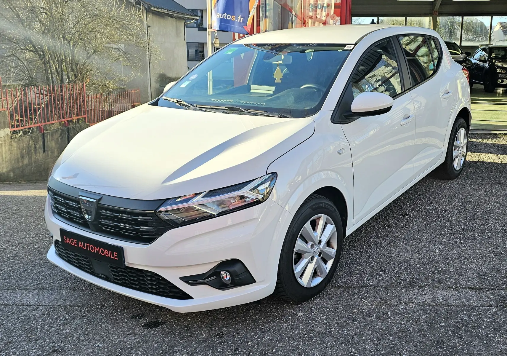 Dacia Sandero III blanc glacier vue 3/4 avant droit, avec calandre noire et jantes alliage argentées.