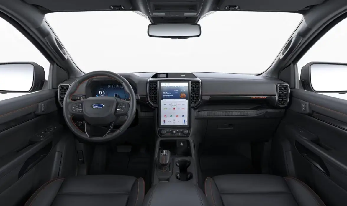 Vue intérieure avant du Ford Ranger Double Cabine 2025 en finition Wildtrak, avec tableau de bord noir et surpiqûres orange.