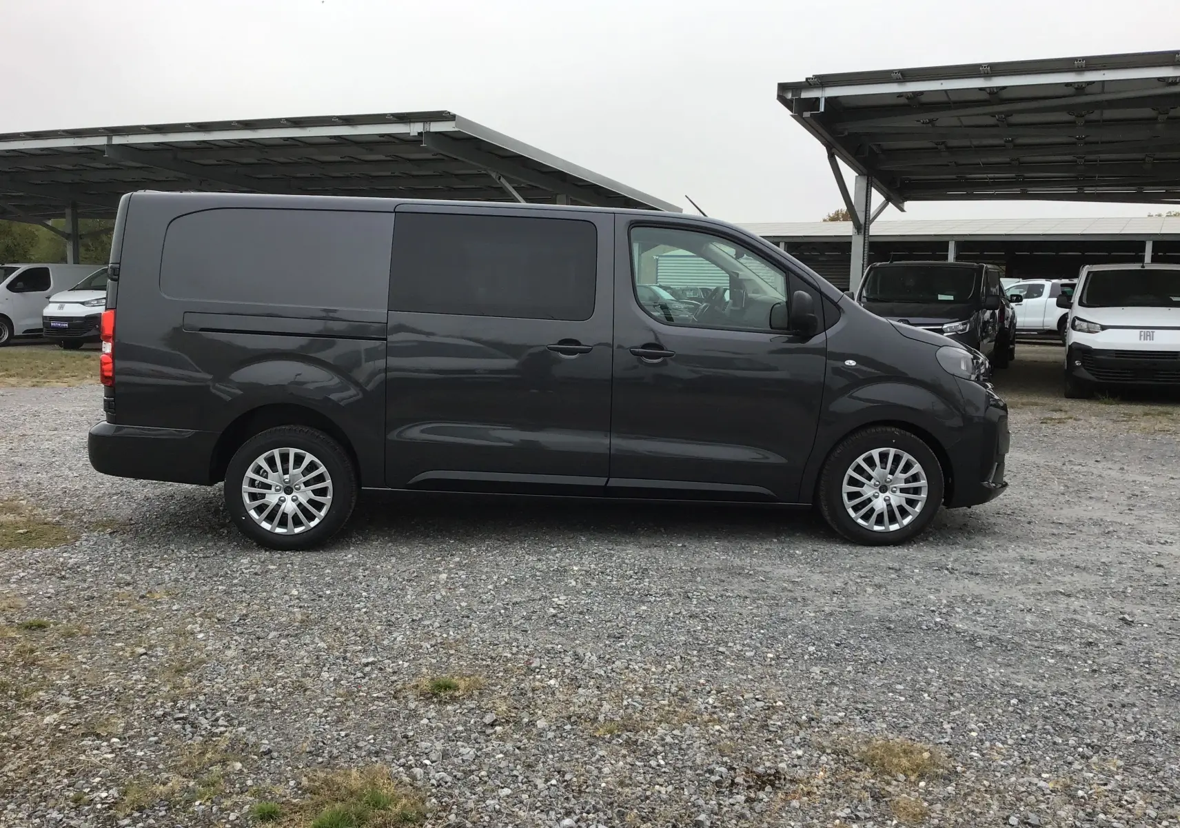 Vue de profil côté gauche d’un Peugeot Expert cabine approfondie gris titane, avec vitres teintées et jantes alliage.