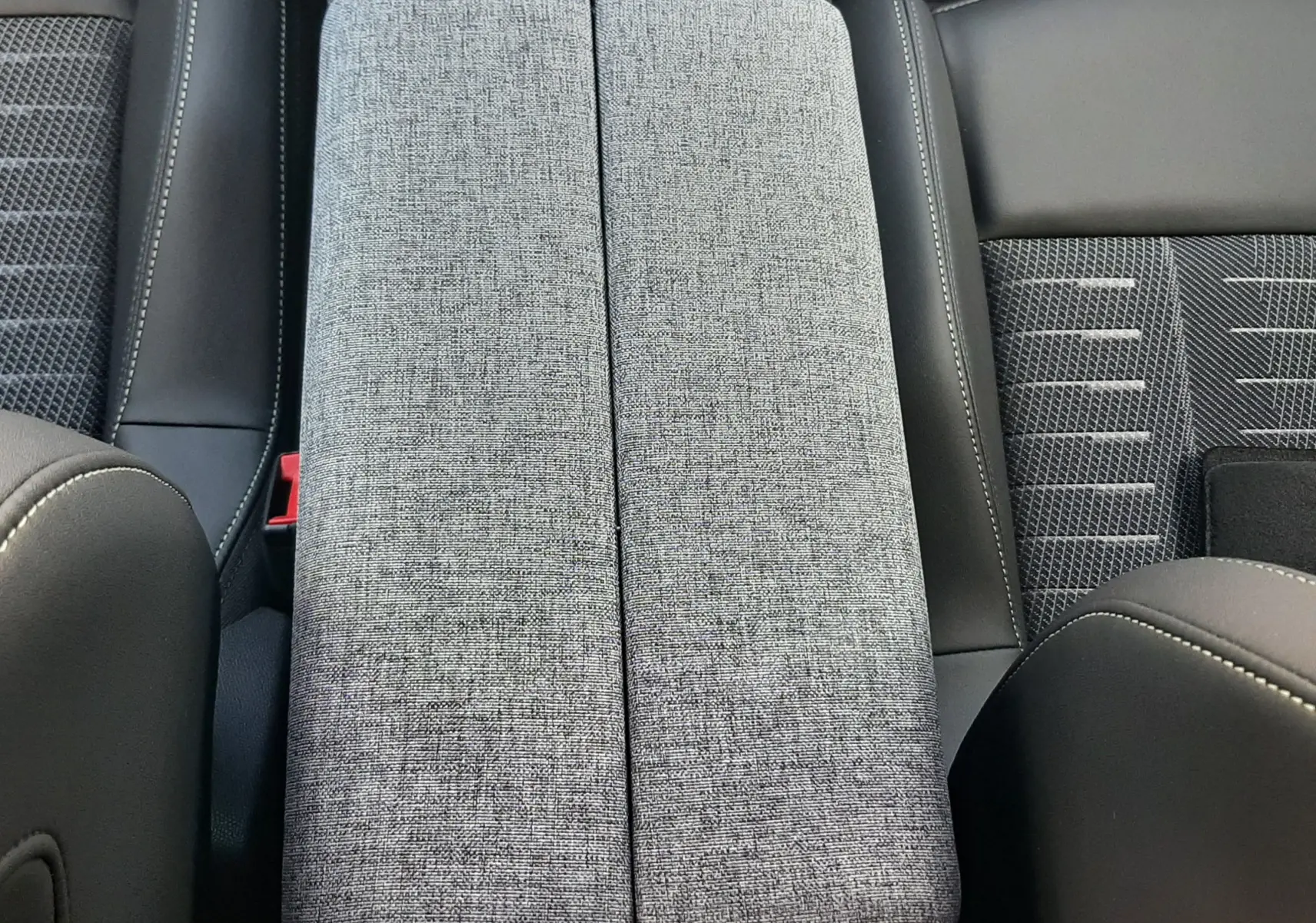 Détail de l'accoudoir central en tissu gris et cuir noir à l'intérieur du Peugeot 3008 Hybrid 145ch GT 2026.