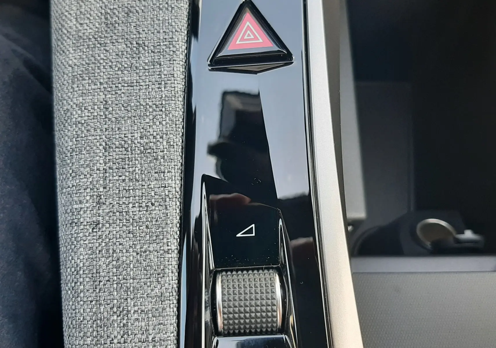 Gros plan sur la console centrale noire brillante du Peugeot 3008 1.2 Hybrid 145ch GT, avec bouton triangle rouge d’alerte.