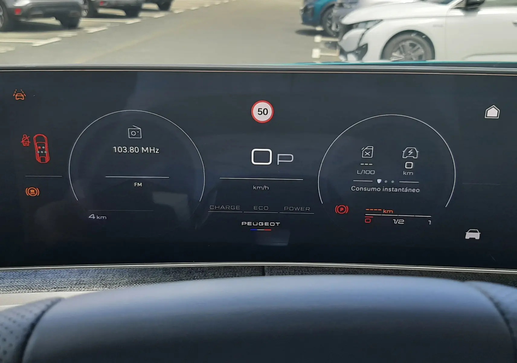 Tableau de bord numérique du Peugeot 3008 Hybrid 2026, affichage central avec vitesse et radio, vue depuis le siège conducteur.