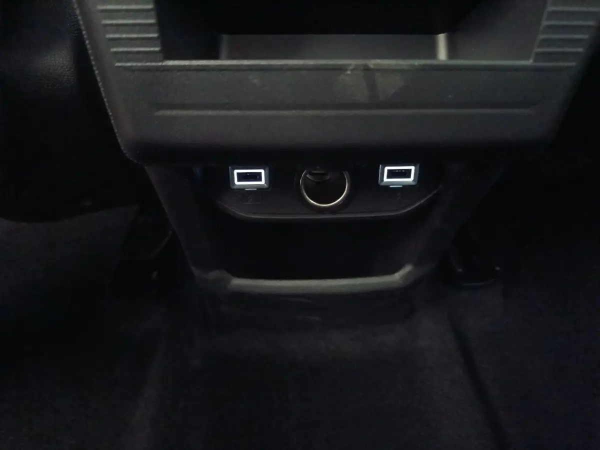 Vue rapprochée des ports USB et prise 12V à l'arrière de la console centrale d'une Citroën C5 Hybride bleu.