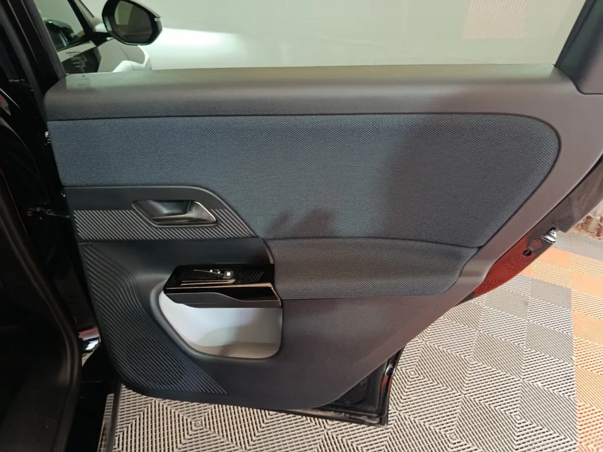Vue intérieure de la porte arrière gauche noire de la Citroën C5 Hybride 2026 avec habillage tissu et commandes de fenêtre.