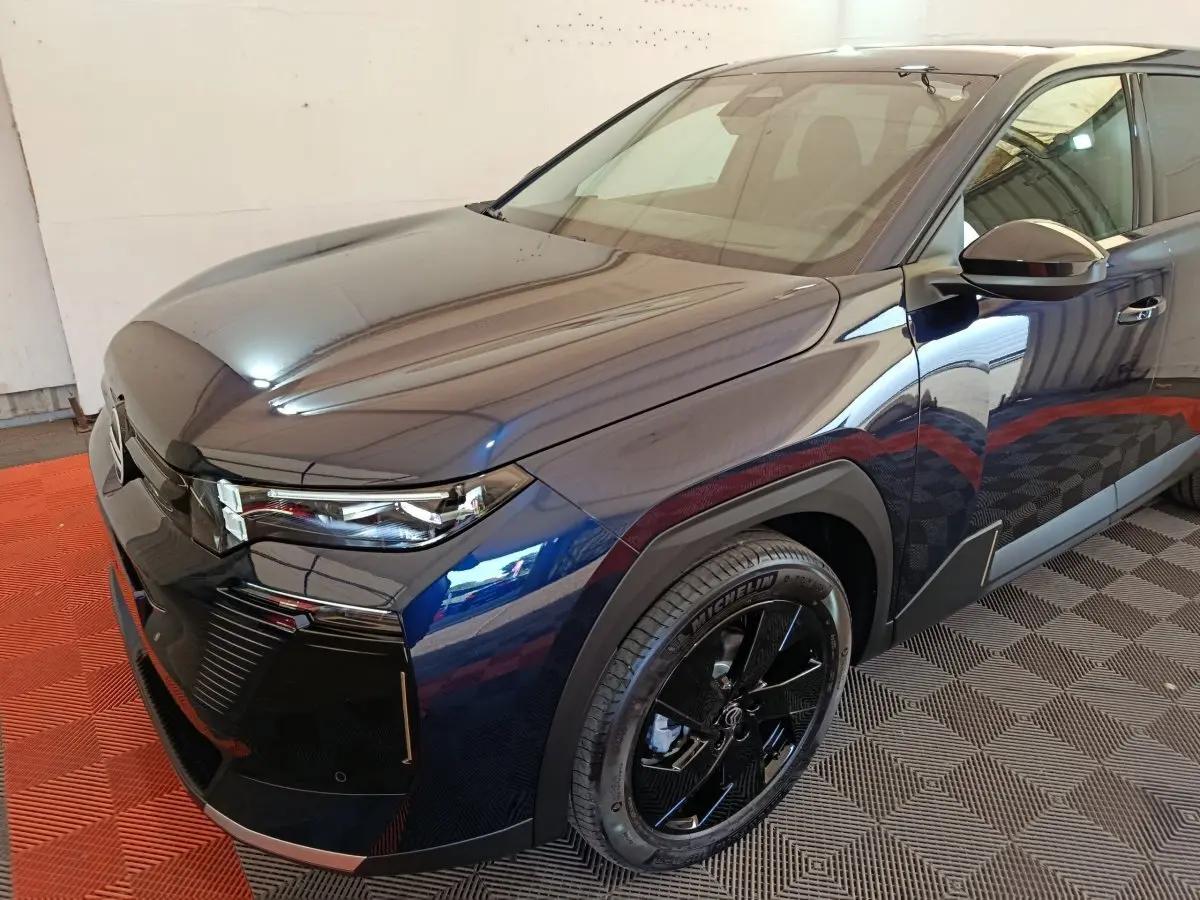 Vue 3/4 avant droit d'une Citroën C5 Hybride bleu foncé avec jantes noires et phares LED modernes.