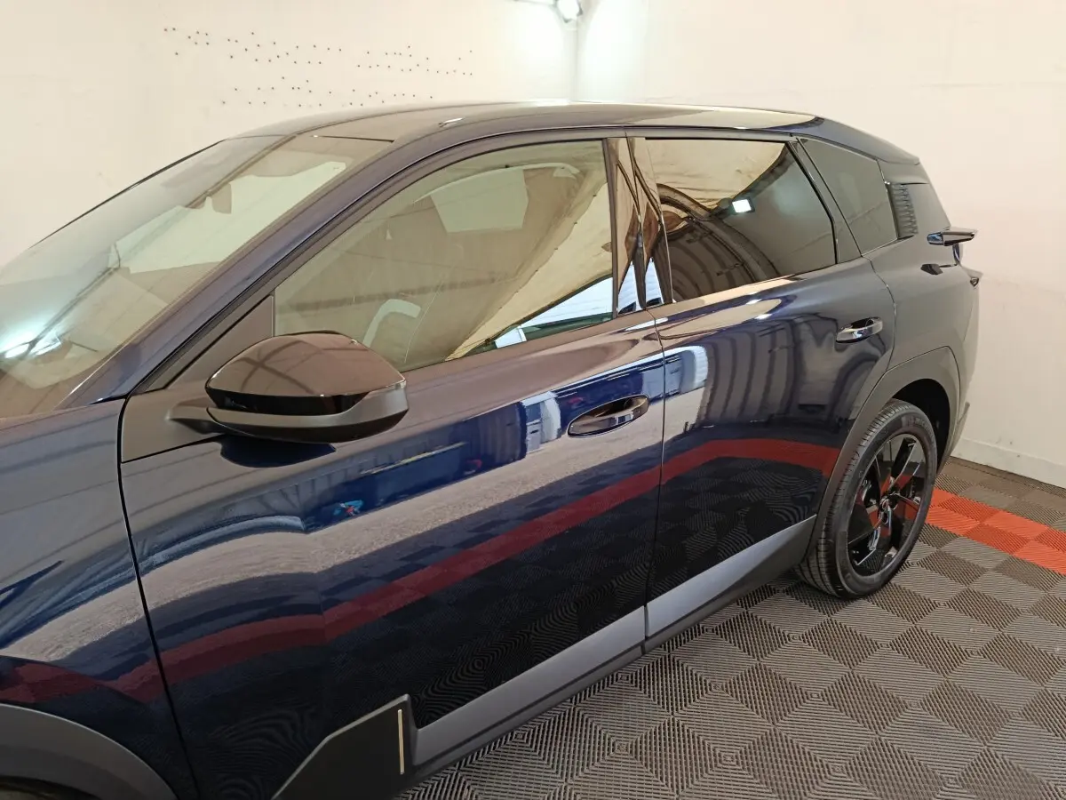 Vue latérale côté gauche d'une Citroën C5 hybride bleu foncé avec rétroviseur noir et jantes noires brillantes.