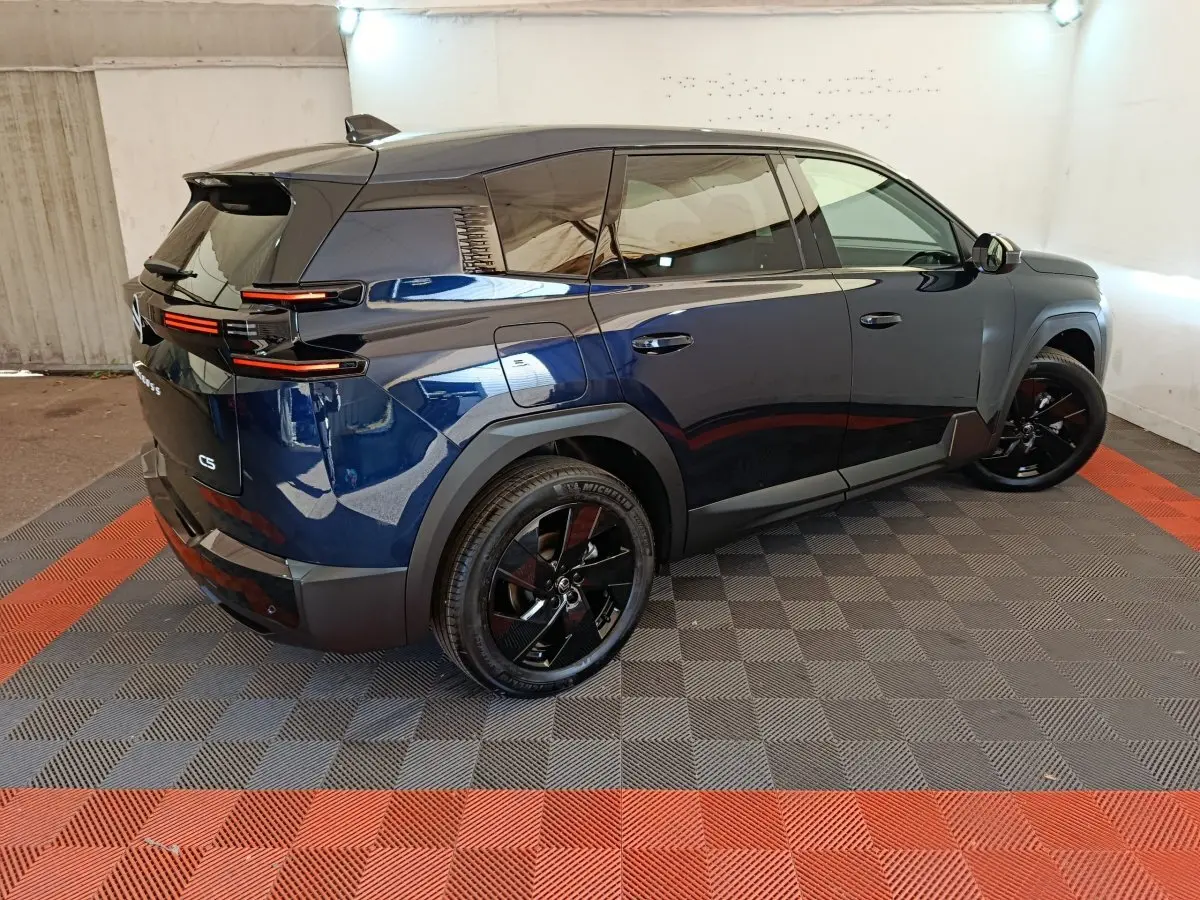 Vue 3/4 arrière droite d'un Citroën C5 hybride bleu avec jantes noires et feux arrière LED distinctifs.