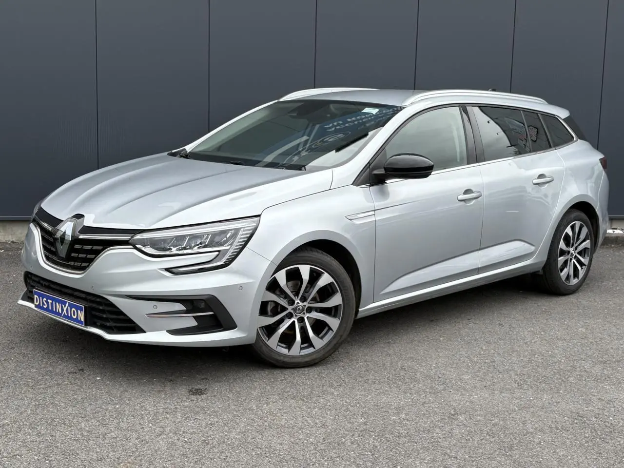 Renault Mégane Break gris Highland vue 3/4 avant droit, avec jantes alliage et rétroviseurs noirs.