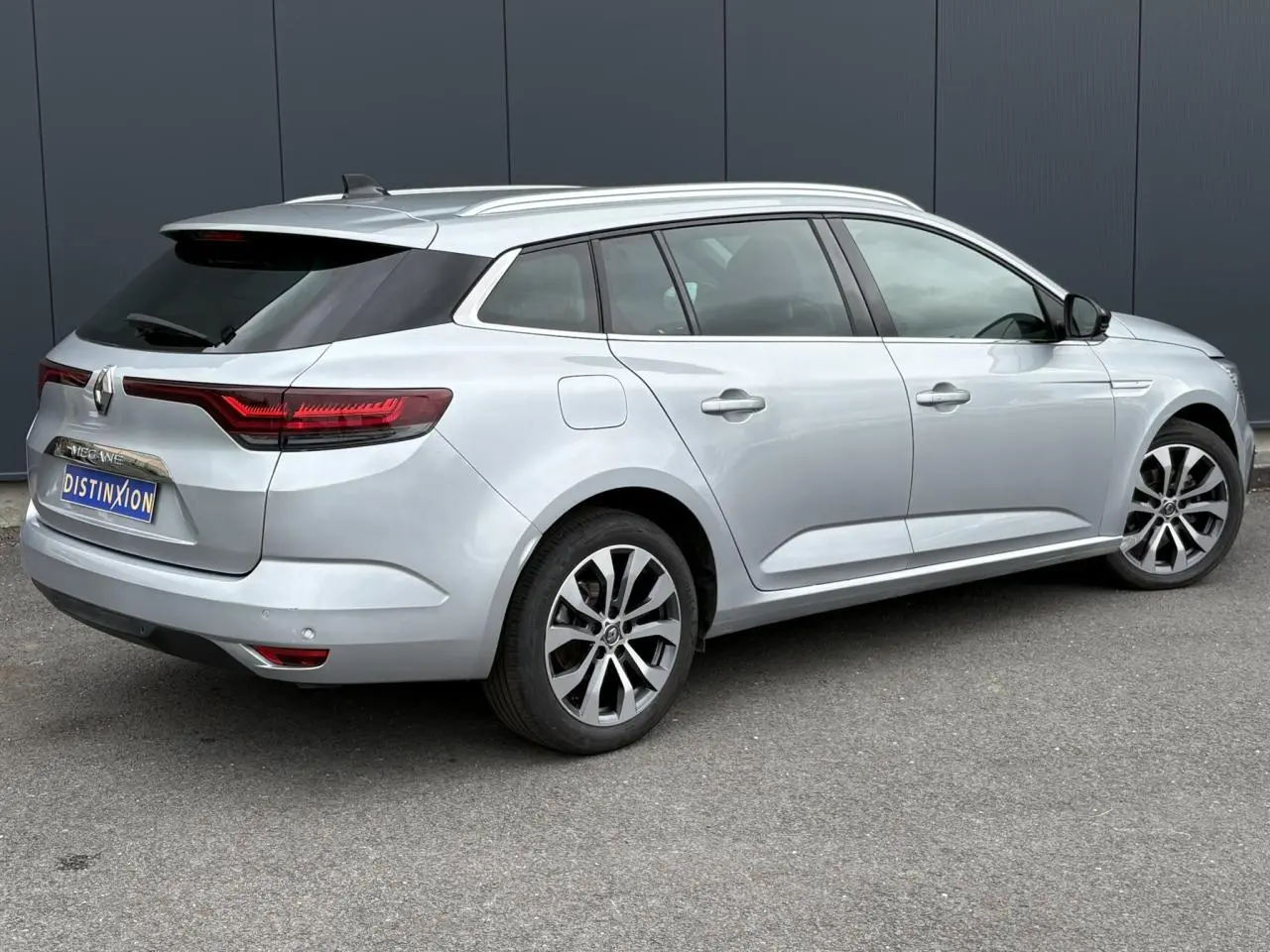 Renault Mégane Break Gris Highland vue 3/4 arrière droit, feux arrière LED et jantes alliage visibles.