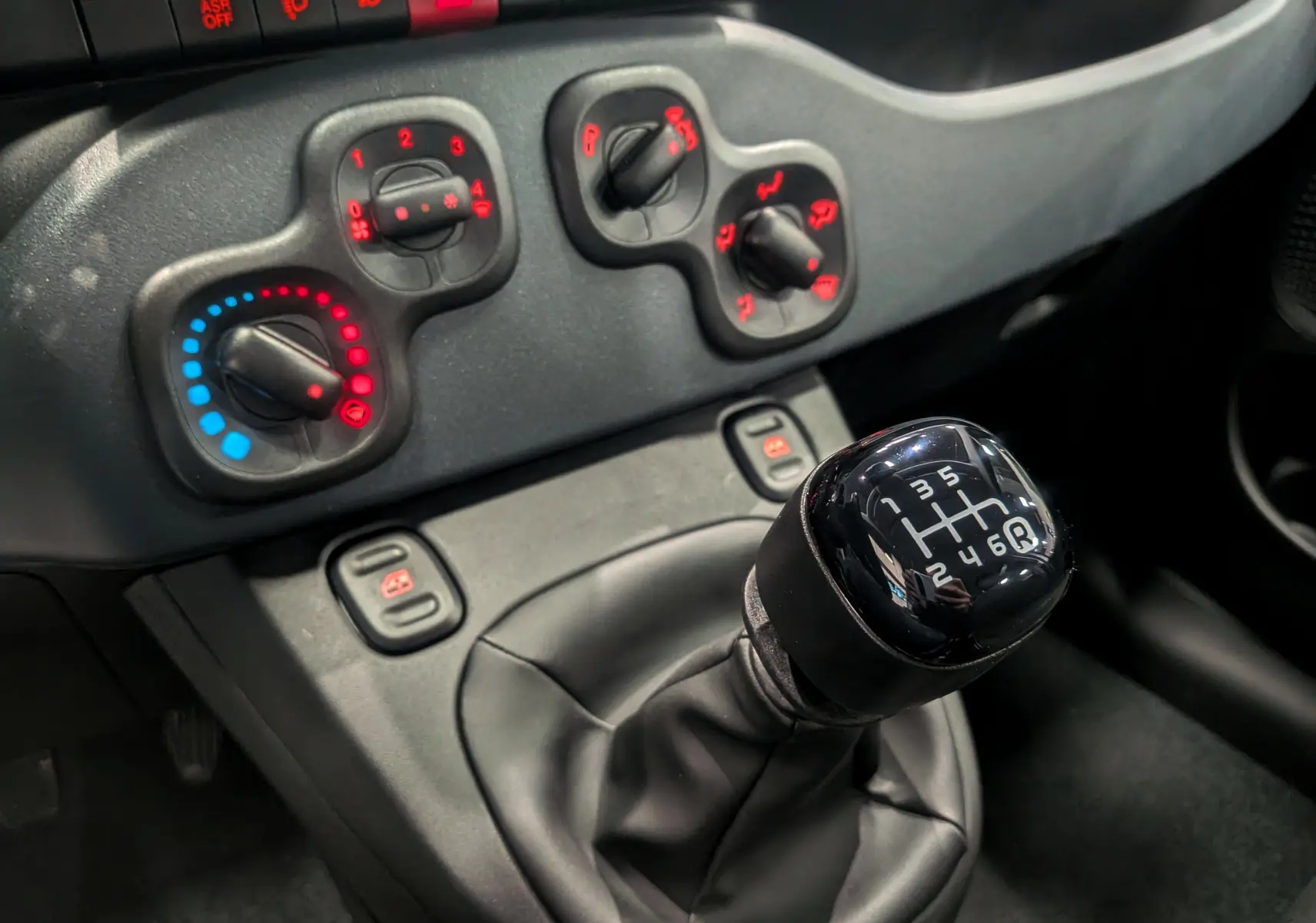 Vue rapprochée de la console centrale de la Fiat Panda 2025, avec levier de vitesse manuel noir et commandes de climatisation.