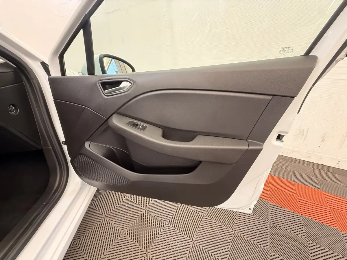 Vue intérieure de la porte avant gauche ouverte d'une Renault Clio Business E-Tech hybride blanche, avec panneau noir et commandes électriques.