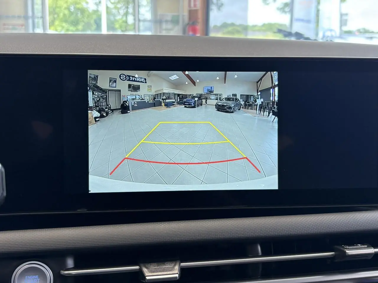 Écran de caméra de recul du Hyundai Tucson blanc Atlas montrant l’intérieur d’un showroom vu de l’arrière du véhicule.
