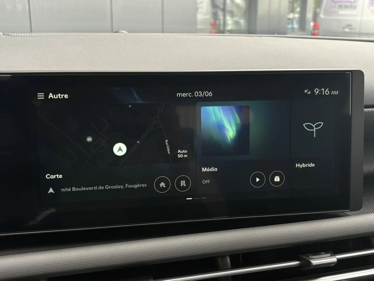 Écran tactile multimédia du Hyundai Tucson 2026 affichant navigation, média et mode hybride, vue intérieure frontale.