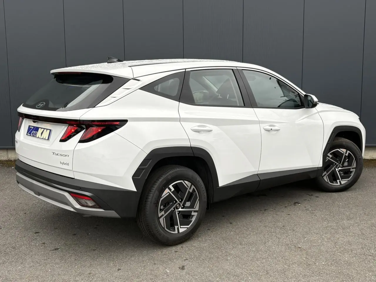 Vue 3/4 arrière droite du Hyundai Tucson blanc Atlas avec jantes alliage 17 pouces et feux arrière LED distinctifs.