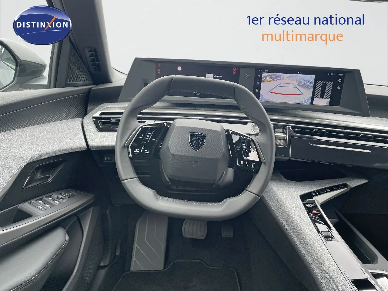 Vue intérieure du poste de conduite du Peugeot 5008 Hybrid 2025, avec volant compact et écran numérique large affichant la caméra de recul.