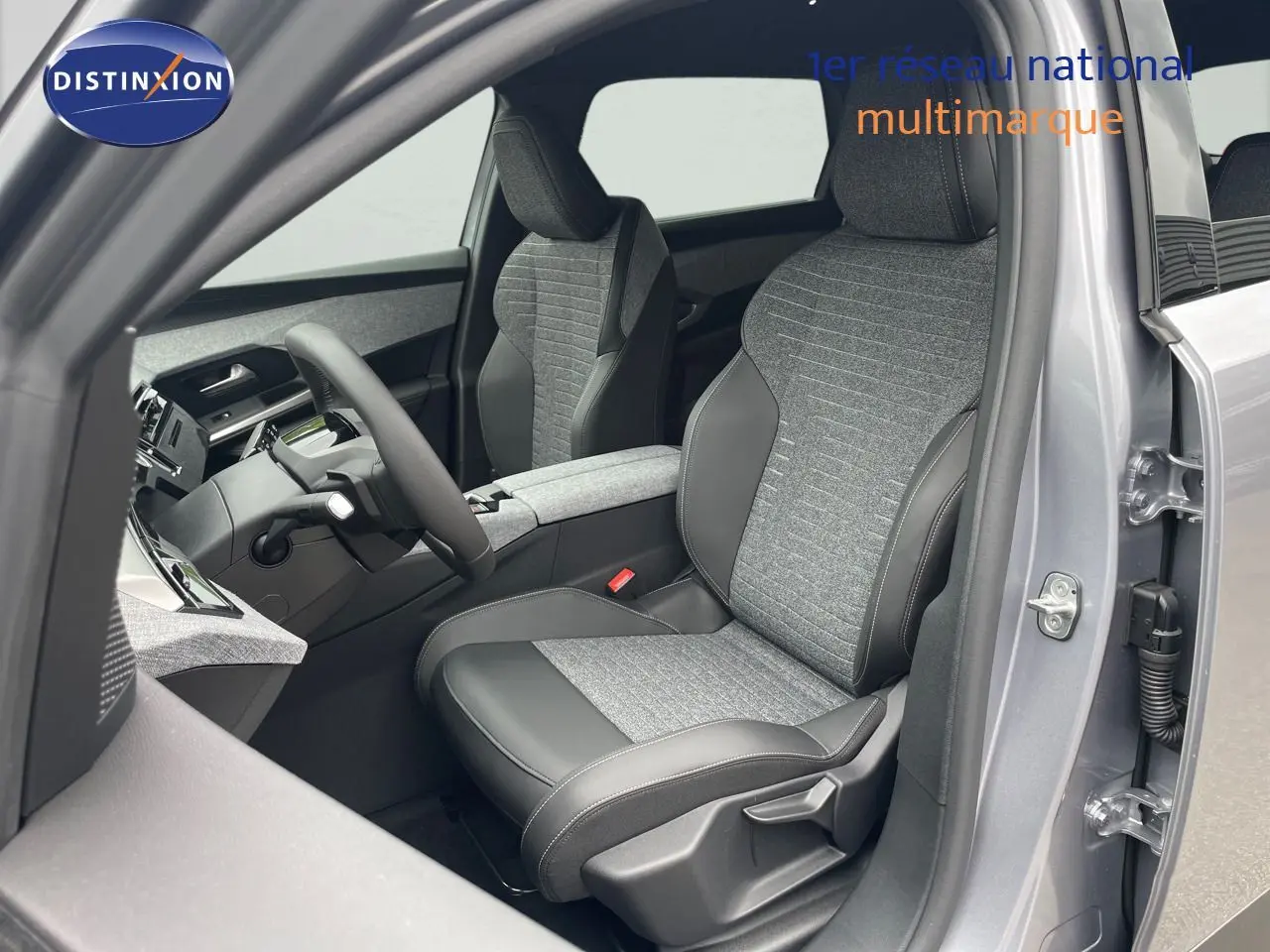 Vue intérieure côté conducteur du Peugeot 5008 gris Artense, sièges tissu et cuir noir avec détails modernes.