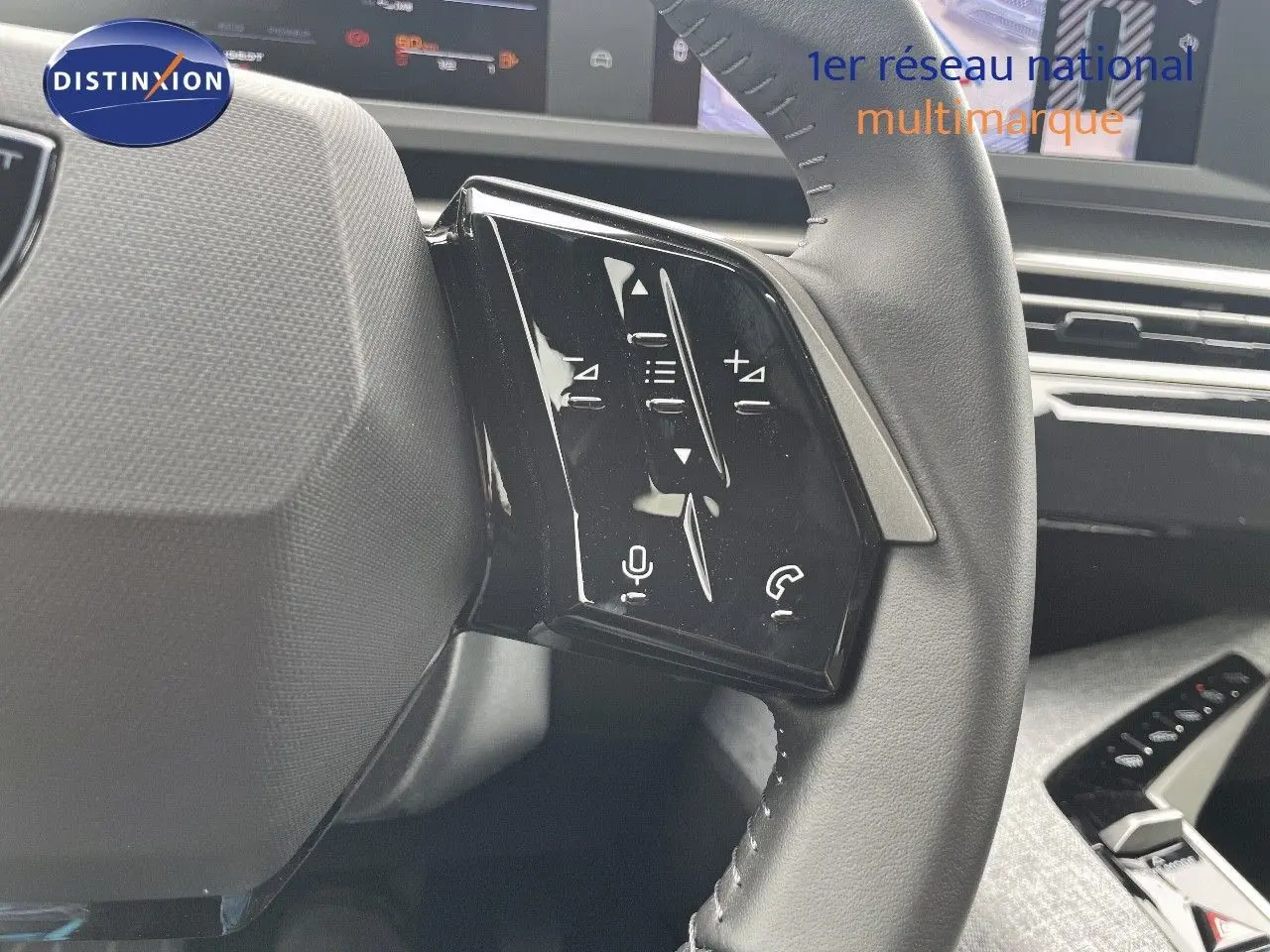Gros plan sur les commandes gauche du volant cuir noir du Peugeot 5008 gris Artense 2025, tableau de bord en arrière-plan.