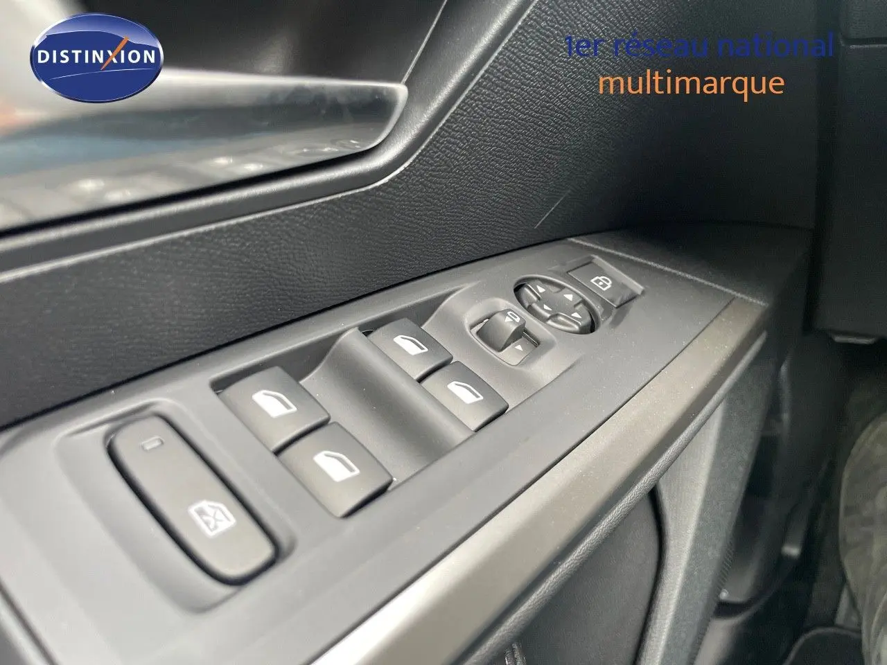 Gros plan sur les commandes des vitres côté gauche dans l'habitacle d'un Peugeot 5008 gris Artense 2025 hybride.