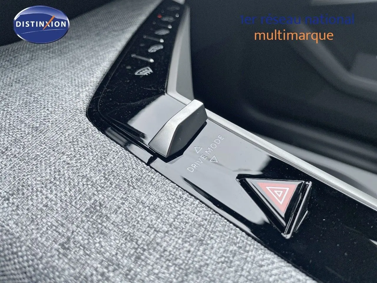 Gros plan sur la console centrale du Peugeot 5008 gris Artense, mettant en valeur le bouton Drive Mode et le triangle de signalisation.