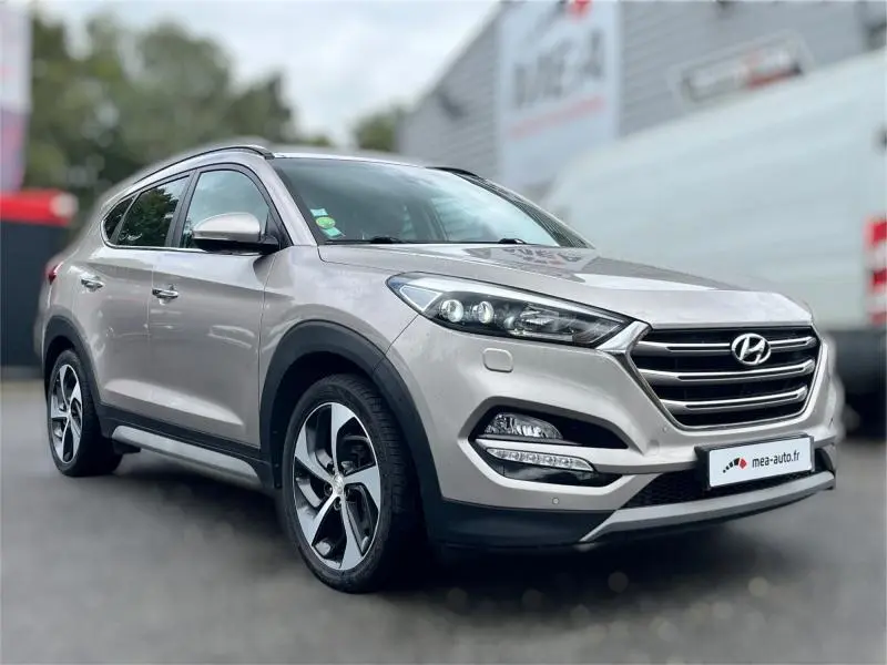 Vue 3/4 avant droite d'un Hyundai Tucson 2017 blanc sable avec calandre chromée et jantes alliage bicolores.