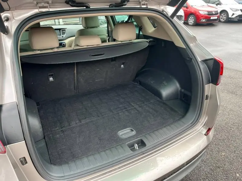 Coffre ouvert vu de l'arrière d'un Hyundai Tucson 2017 White Sand avec cache-bagages et intérieur beige.