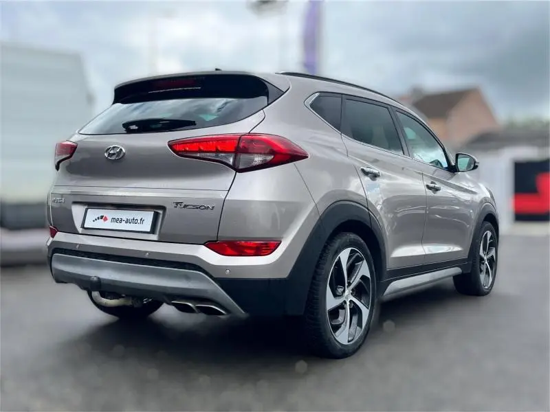 Vue 3/4 arrière droite du Hyundai Tucson 2017 blanc sable avec feux arrière LED et jantes alliage distinctives.