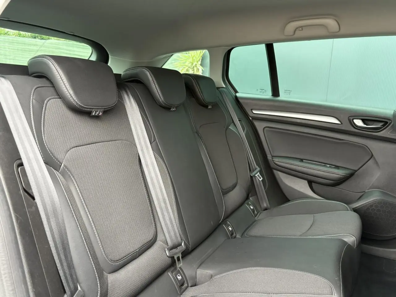 Vue latérale droite de la banquette arrière en tissu noir avec appuie-têtes et ceintures dans une Renault Mégane Break 2024.