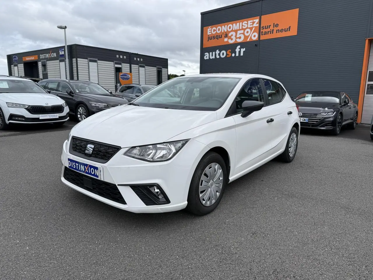 SEAT Ibiza blanc candy vue 3/4 avant droit, avec jantes enjoliveurs et rétroviseurs noirs sur parking.