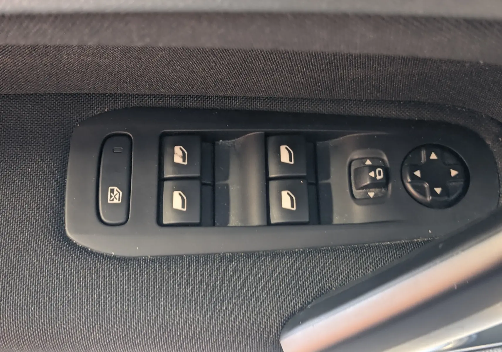 Gros plan sur les commandes de lève-vitres et réglages des rétroviseurs côté conducteur d’une Peugeot 308 noire.