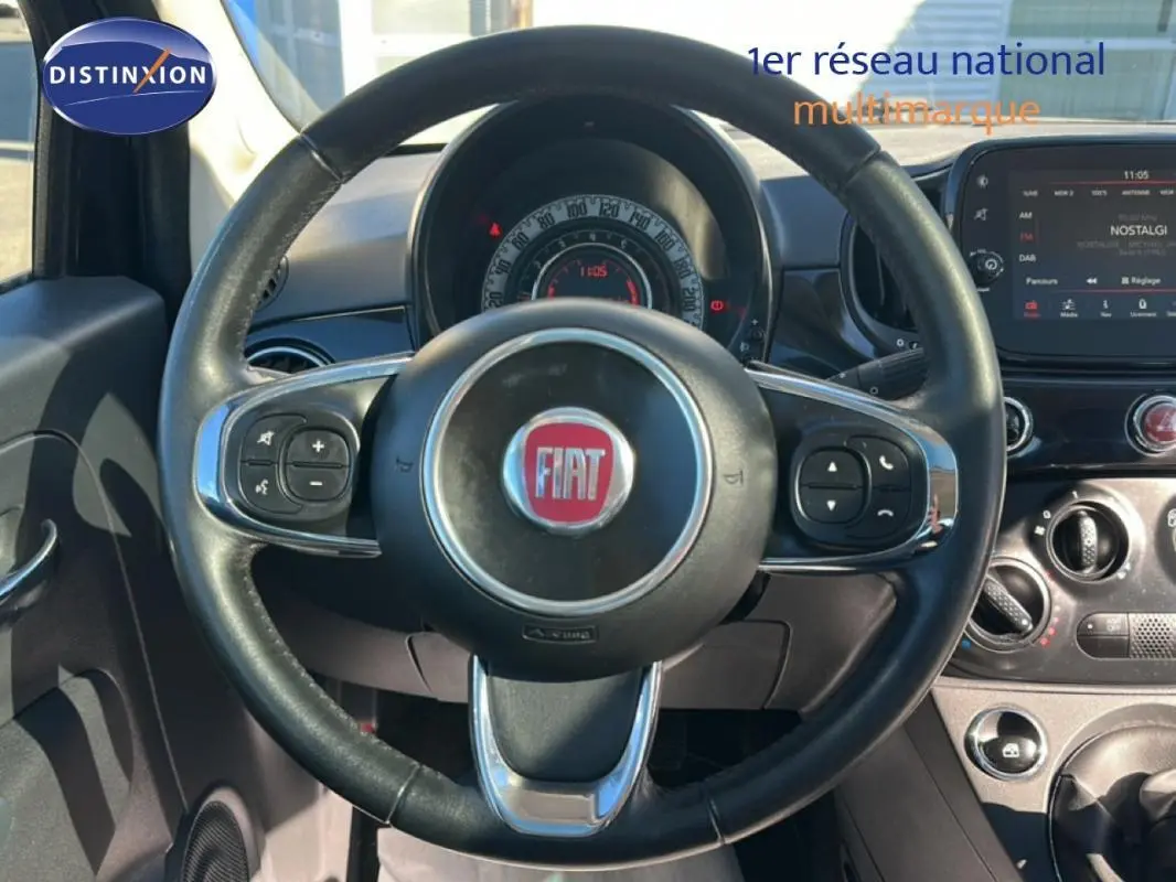 Vue rapprochée du volant noir de la Fiat 500 Lounge 2016 avec tableau de bord et écran tactile visible.