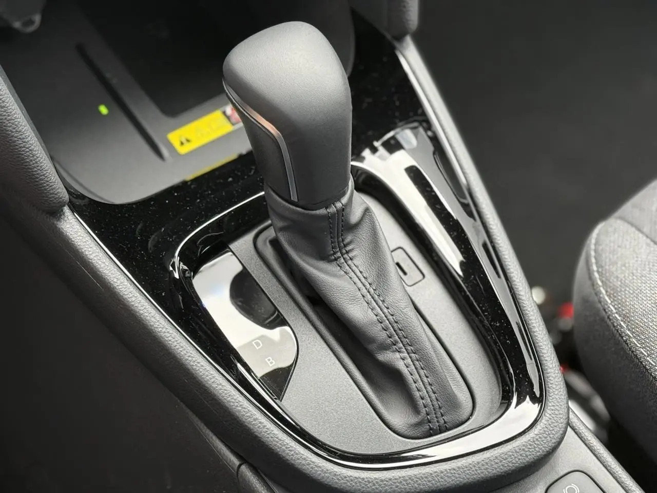 Gros plan sur le levier de vitesses automatique noir de la Toyota Yaris Cross 1.5 Hybrid 2026, intérieur gris.