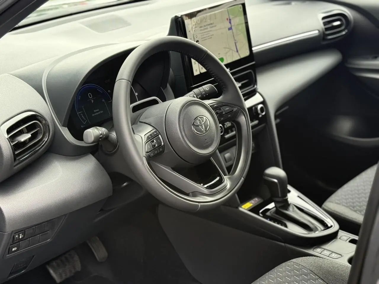 Vue intérieure côté conducteur de la Toyota Yaris Cross 1.5 Hybrid 116 Design avec volant cuir et écran tactile central.