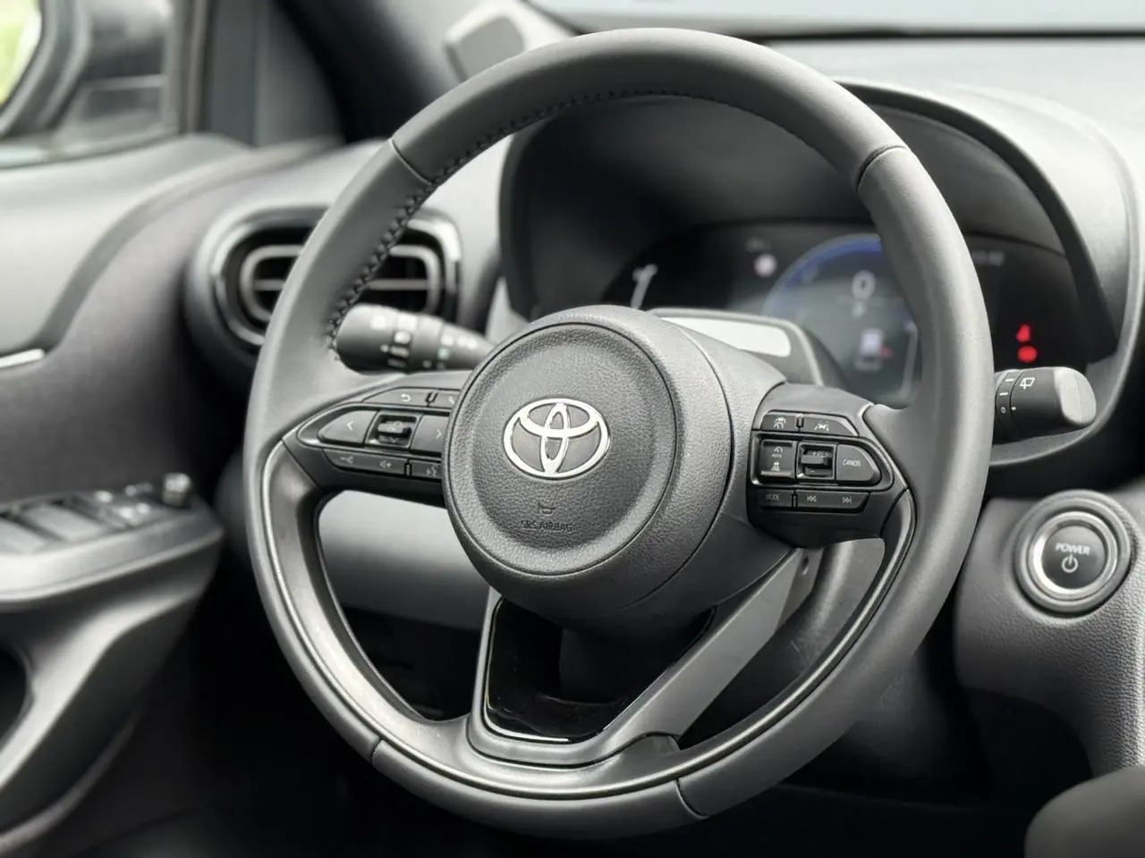 Vue rapprochée du volant cuir noir de la Toyota Yaris Cross 2026 avec commandes intégrées et bouton start.