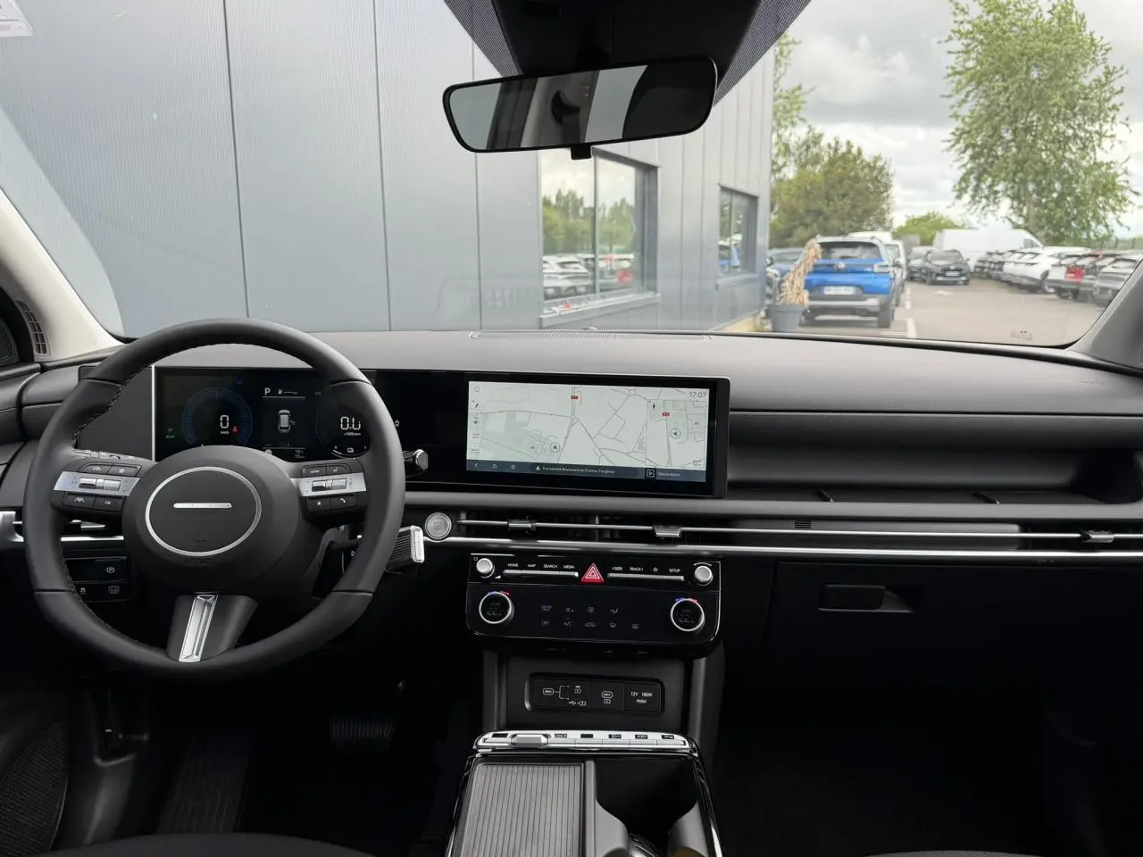 Vue intérieure avant du Hyundai Tucson 2026, tableau de bord noir avec écran tactile large affichant la navigation.