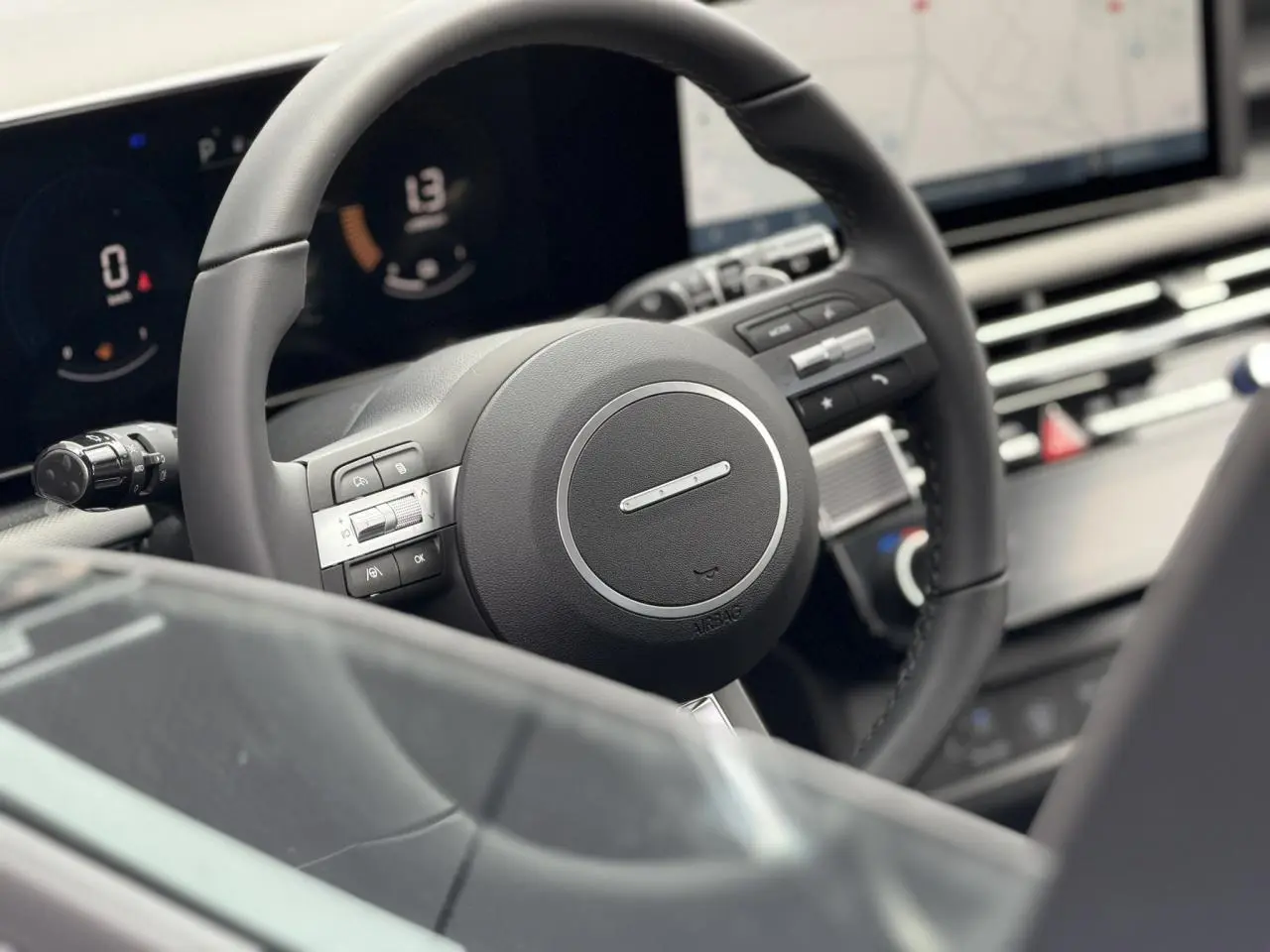 Gros plan sur le volant noir du Hyundai Tucson 2026 avec tableau de bord numérique et écran tactile en arrière-plan.