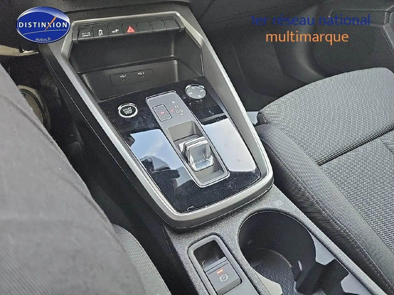 Gros plan sur la console centrale noire brillante avec levier de boîte automatique et siège tissu gris de l'Audi A3 Sportback 2024