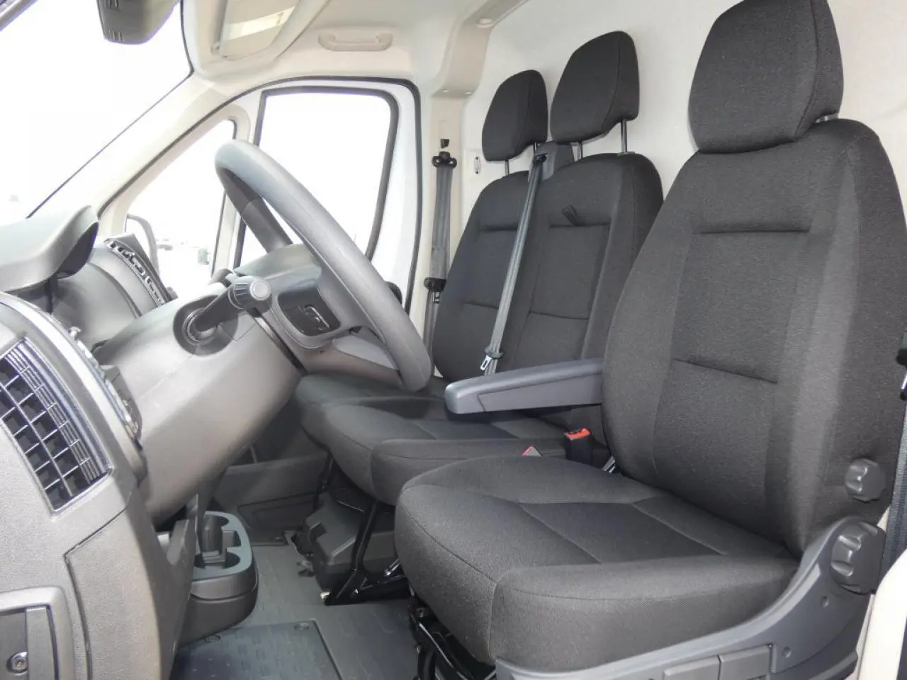 Vue intérieure côté conducteur du Citroën Jumper 2025, sièges noirs et volant en cuir visible.