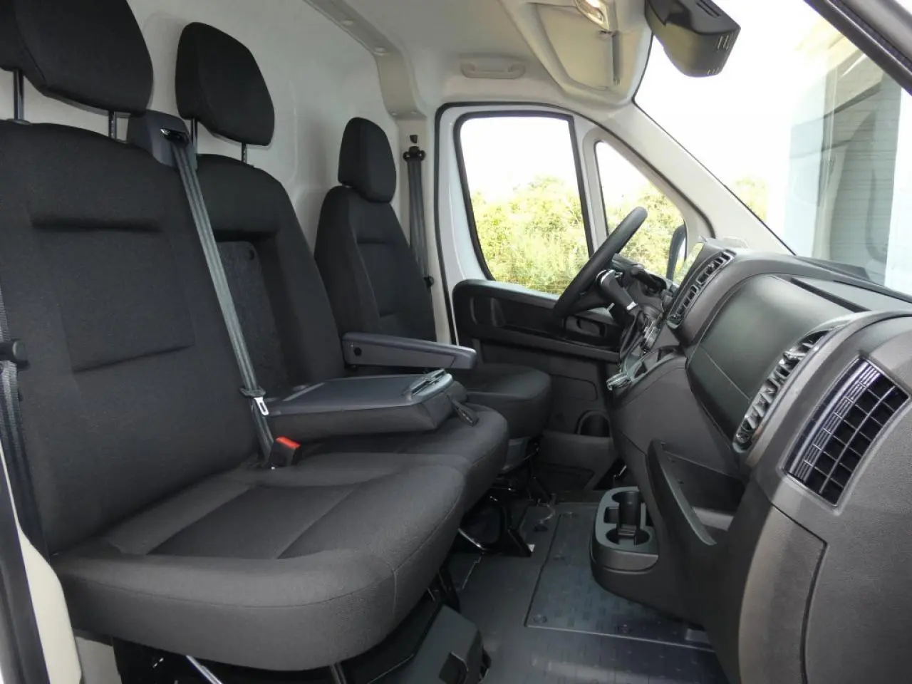 Vue intérieure côté conducteur du Citroën Jumper 2025 blanc, montrant les sièges noirs et le tableau de bord moderne.