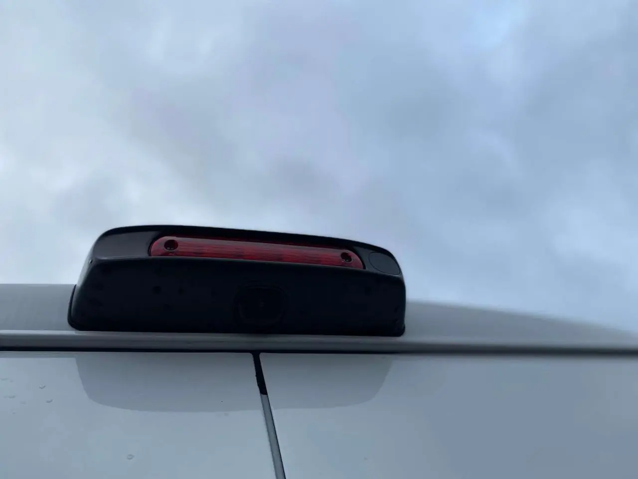 Gros plan sur la caméra de recul intégrée au feu stop supérieur arrière du Citroën Jumper blanc.