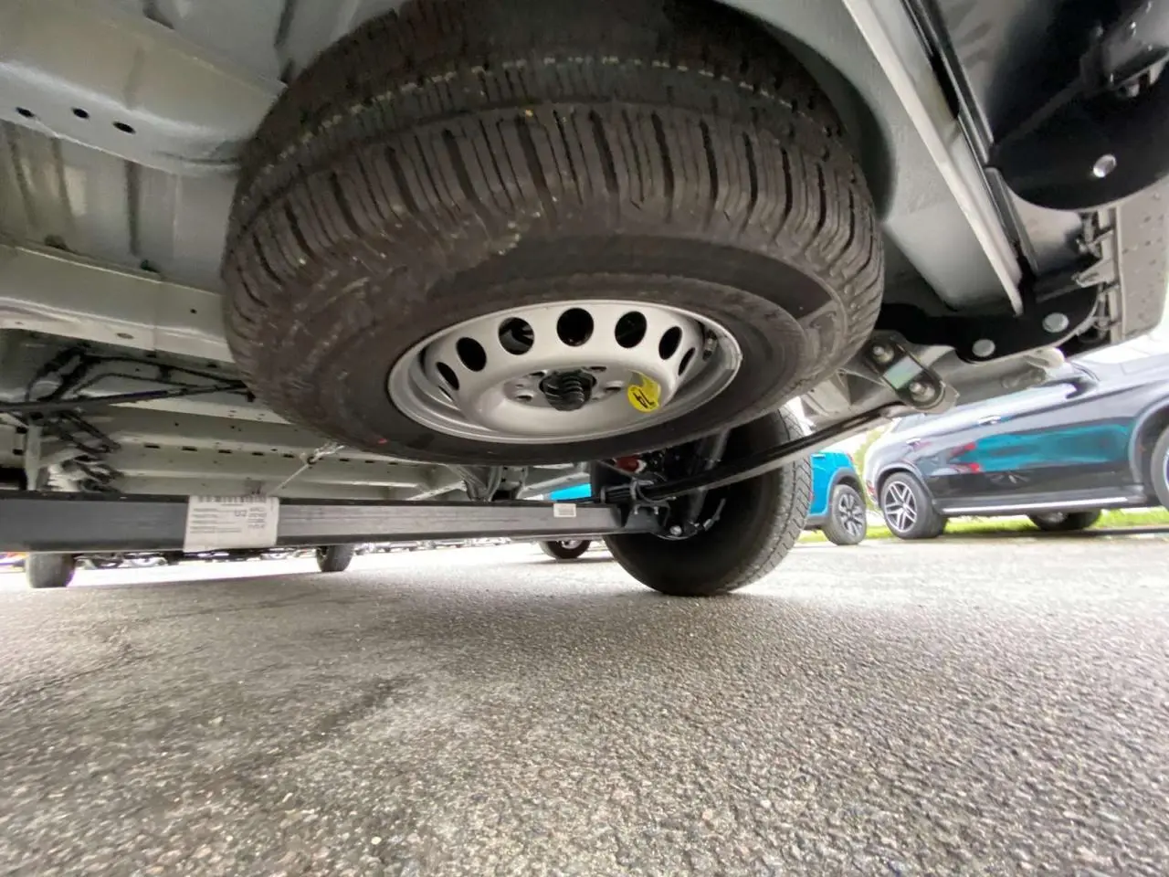 Vue en contre-plongée sous un Citroën Jumper blanc 2025, montrant la roue de secours sous le châssis arrière.