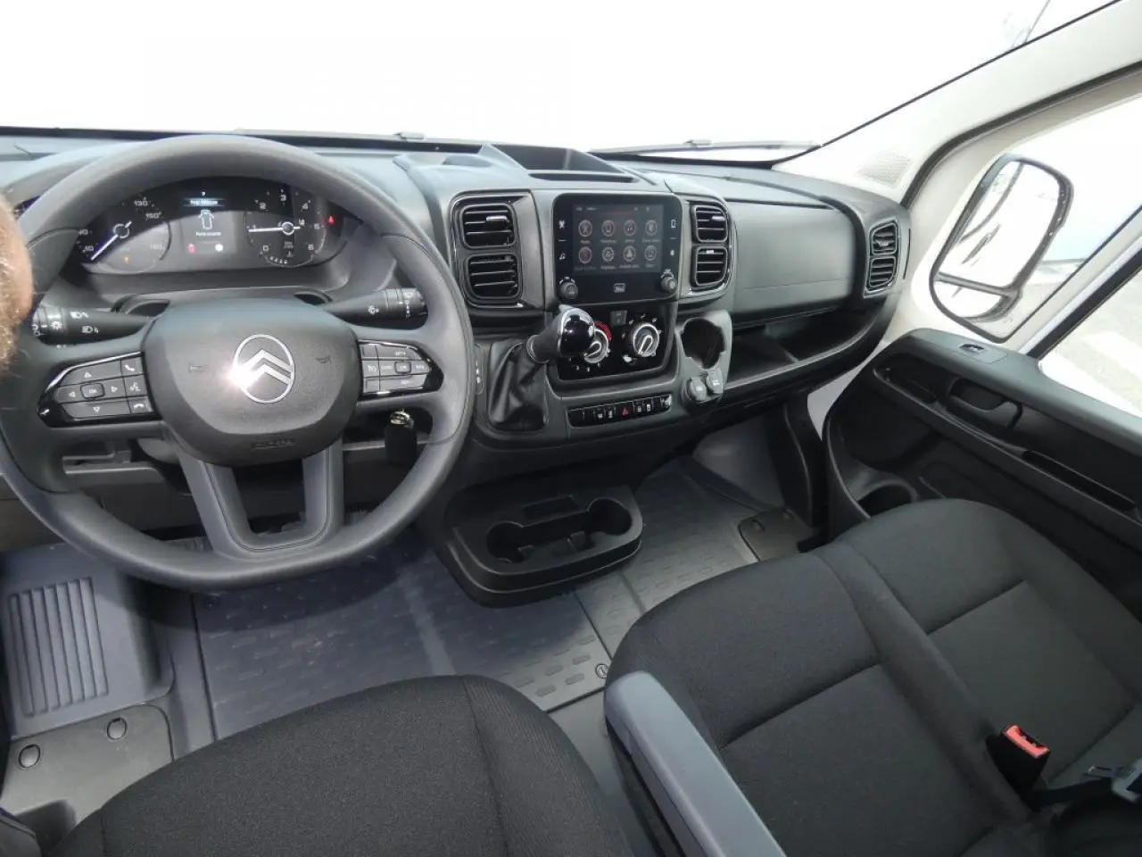 Vue intérieure côté conducteur du Citroën Jumper 2025, tableau de bord noir avec écran tactile central et volant multifonction.