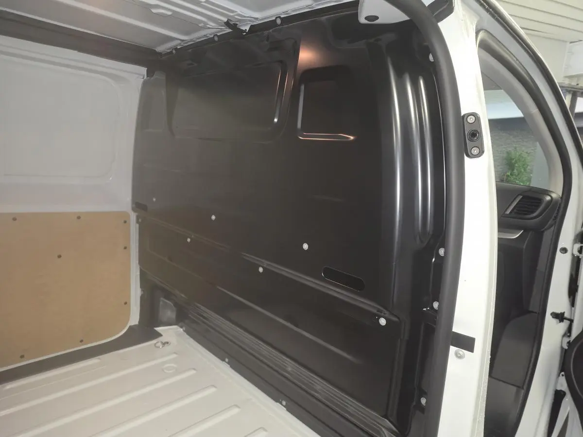 Vue intérieure côté droit du compartiment de chargement blanc de l’Opel Vivaro M 2.0 BlueHDi avec cloison noire tôlée.