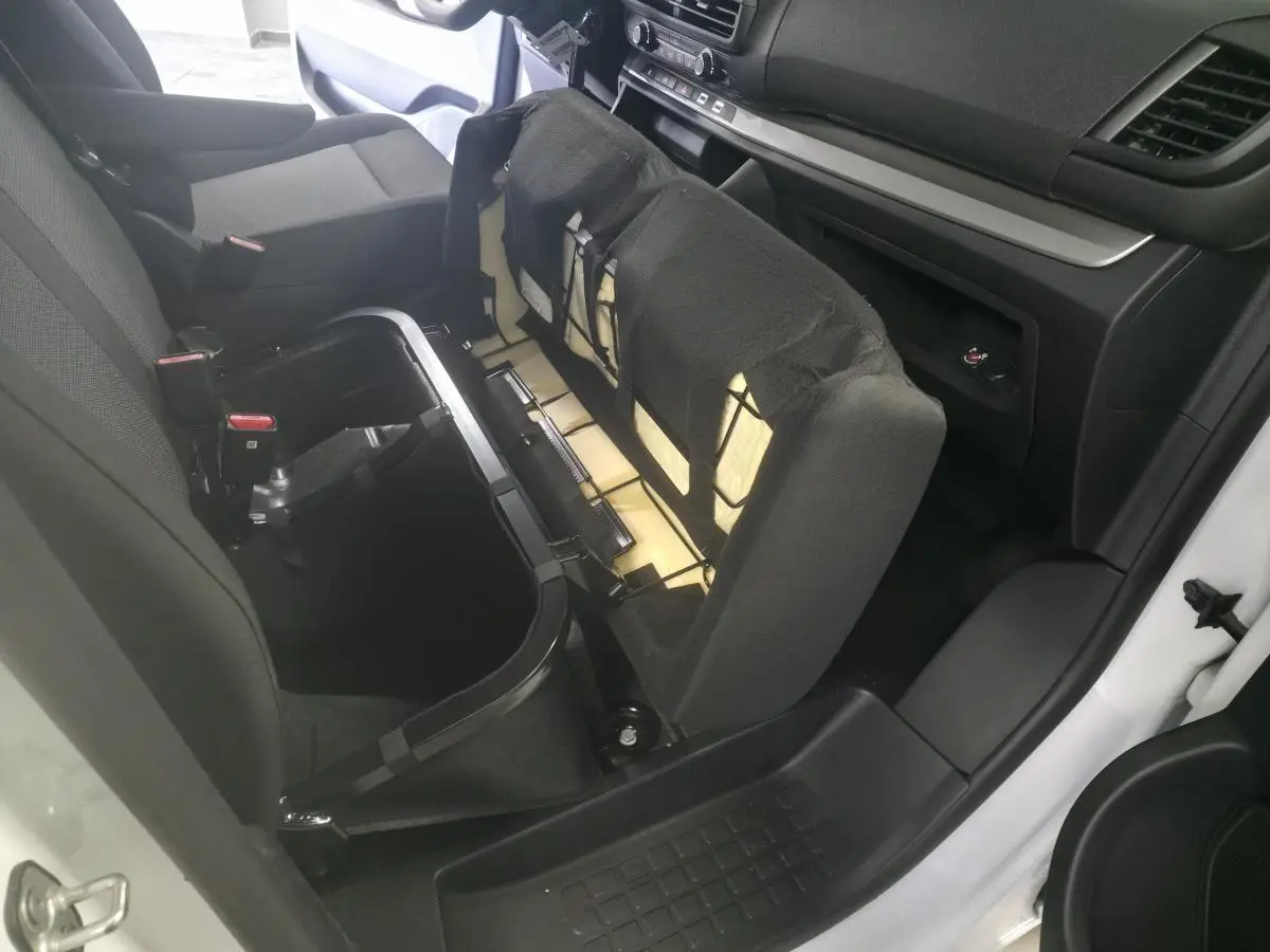 Vue intérieure côté droit du coffre sous la banquette relevée d'un Opel Vivaro blanc, montrant le rangement intégré.