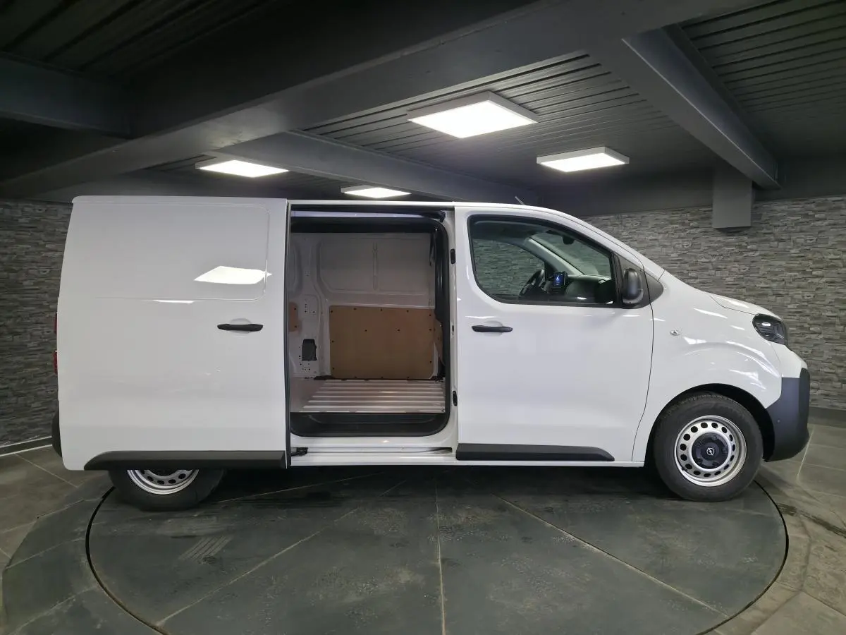 Vue latérale droite d'un Opel Vivaro blanc 2025 avec porte coulissante ouverte montrant l'espace de chargement vide.