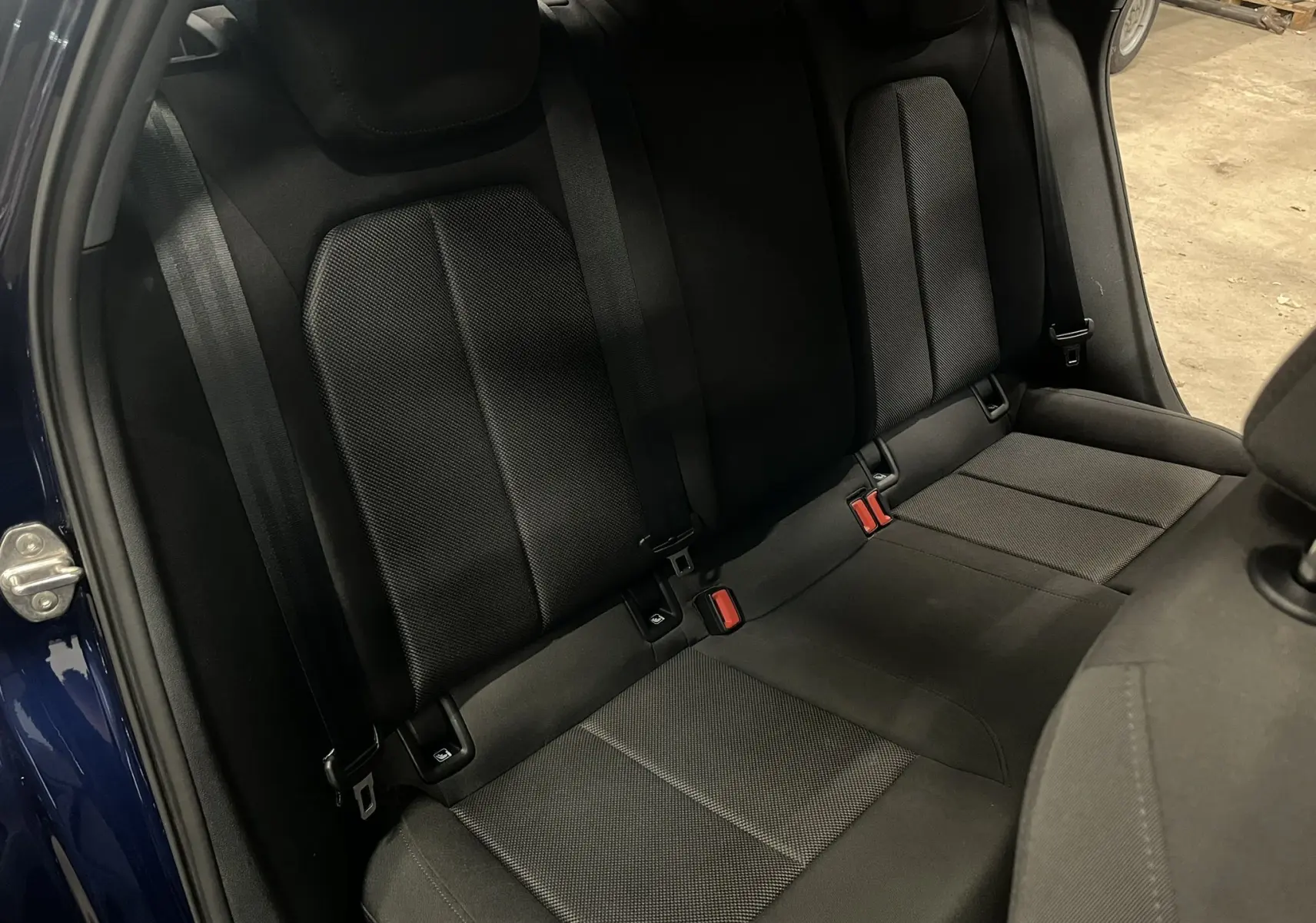 Vue intérieure de la banquette arrière noire de l'Audi A3 Sportback 30 TFSI, avec ceinture et fixation ISOFIX visibles.