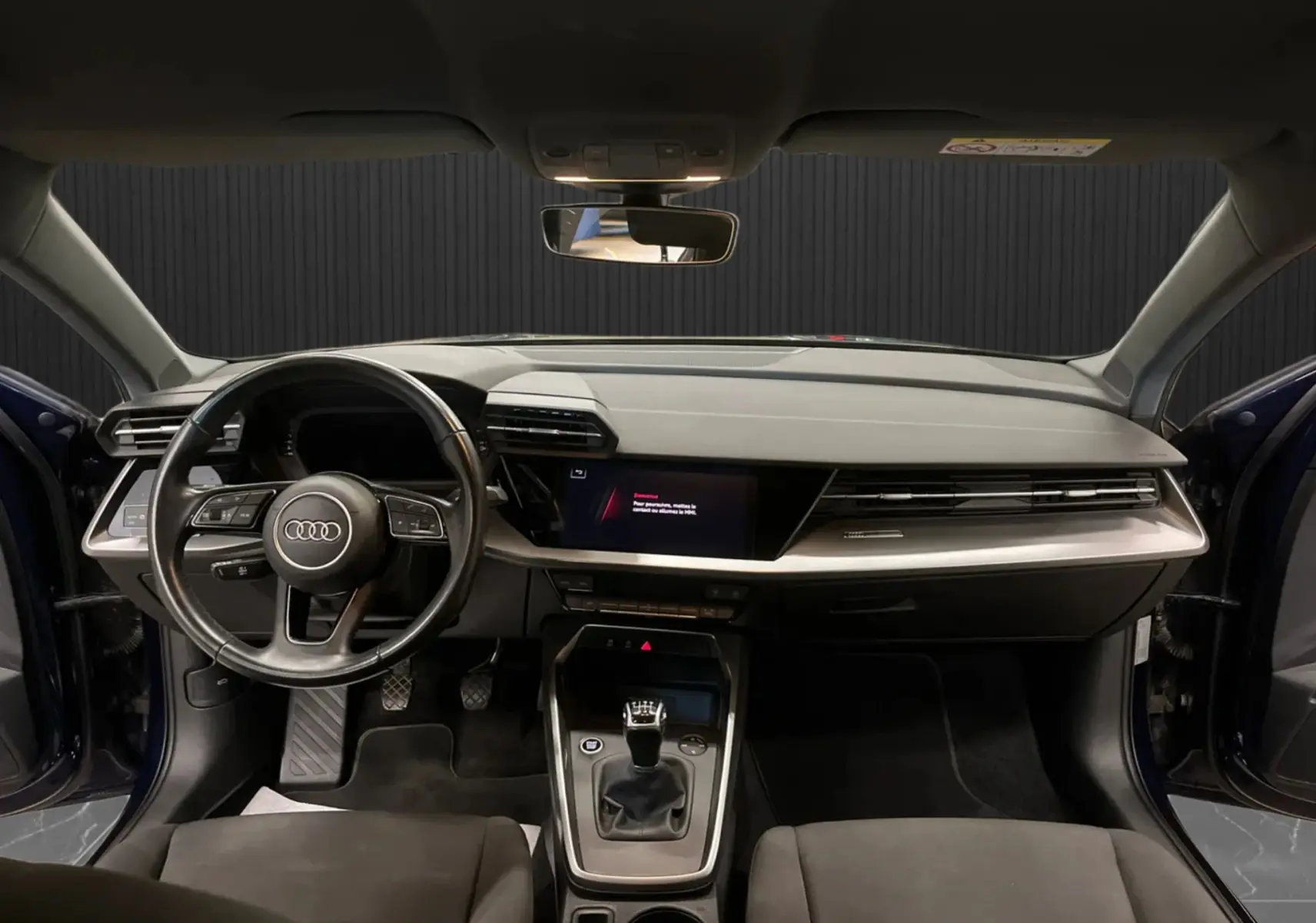 Vue intérieure avant de l'Audi A3 Sportback 30 TFSI bleu métallisé, avec tableau de bord moderne et volant multifonction.