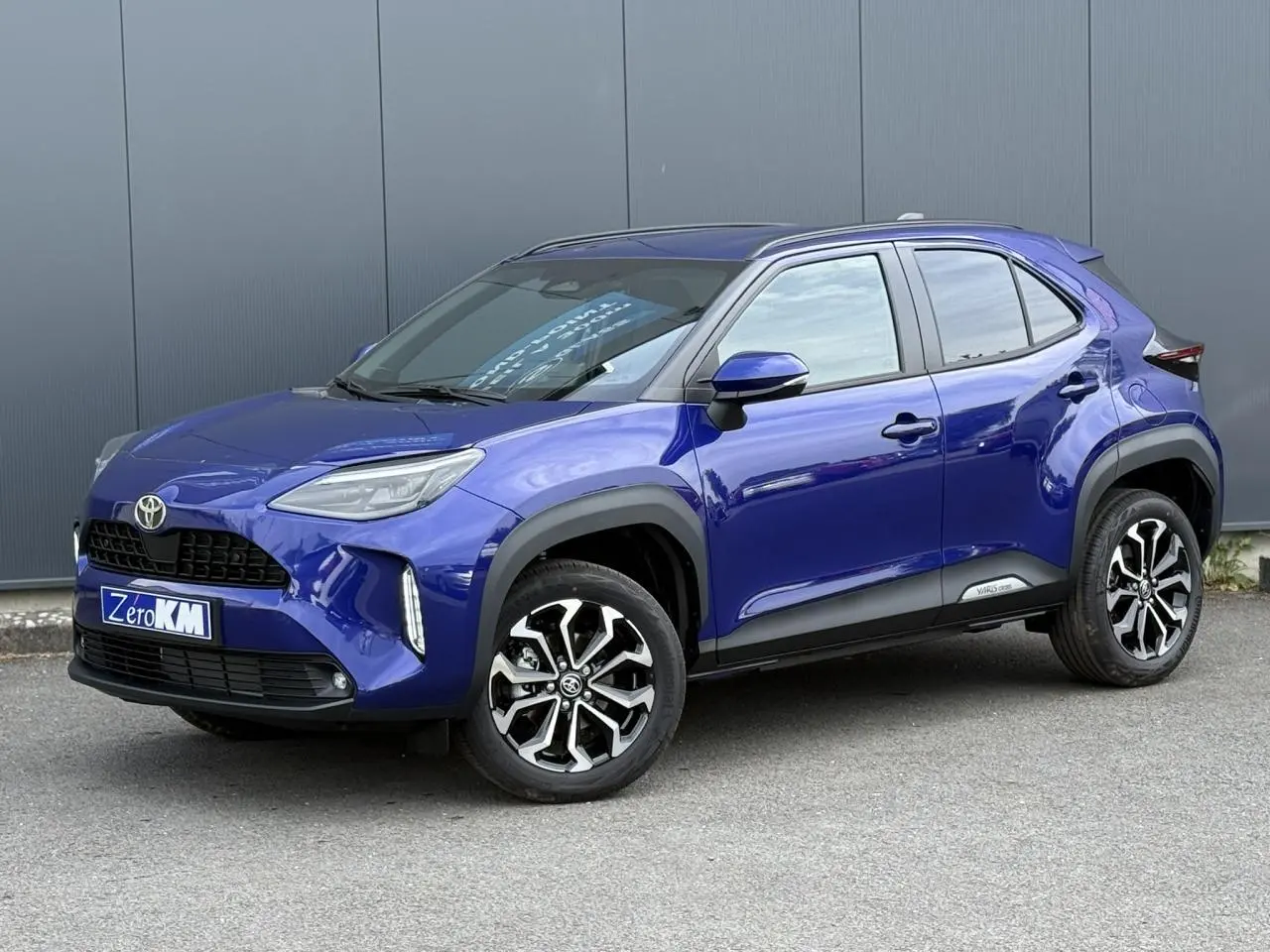 Toyota Yaris Cross bleu Genievre en 3/4 avant droit avec jantes alliage et protections noires sur carrosserie
