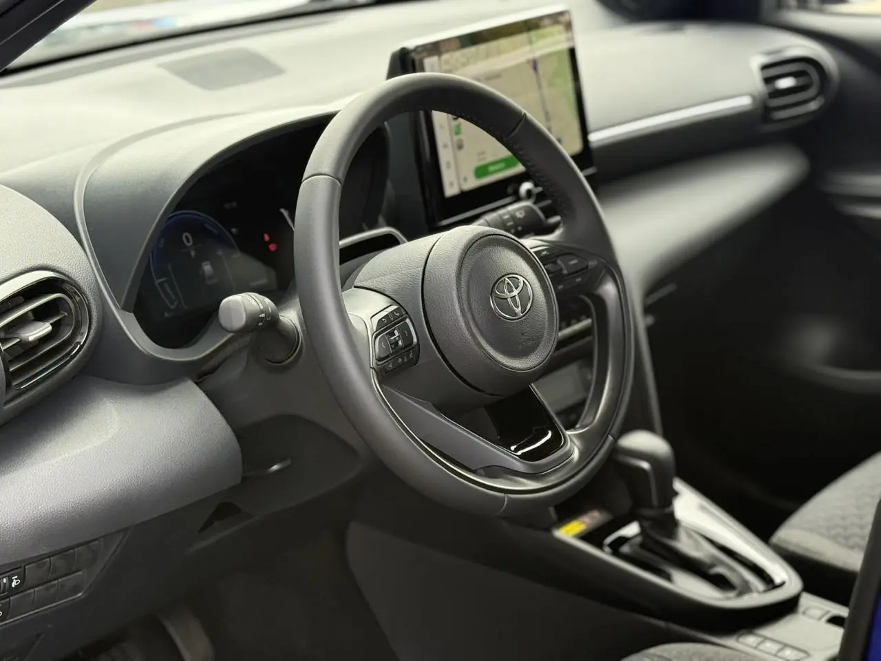 Vue intérieure côté conducteur du Toyota Yaris Cross 2026, volant cuir et écran tactile central visible.