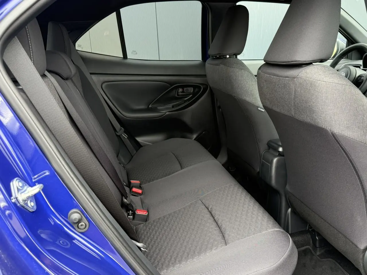 Vue intérieure côté gauche des sièges arrière noirs d’une Toyota Yaris Cross 1.5 Hybrid 116 Design bleu Genievre.