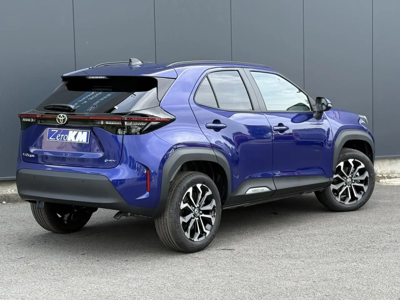 Toyota Yaris Cross bleu Genievre en 3/4 arrière droit, avec jantes noires et toit noir contrasté.